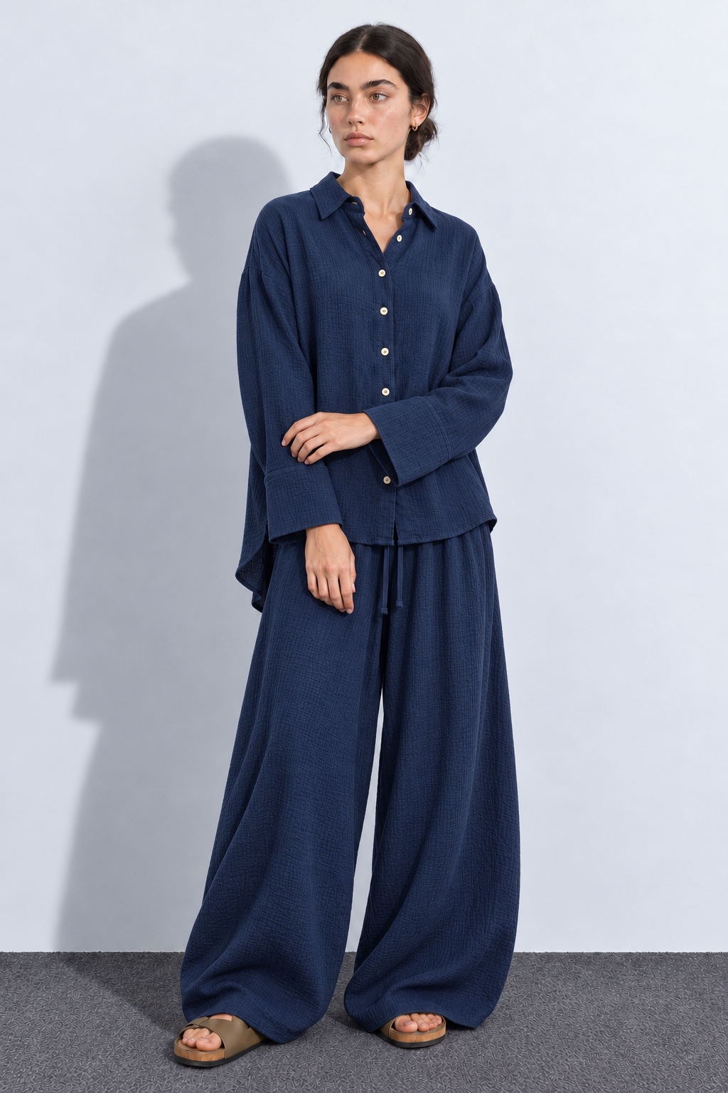 Model wearing a navy crinkle co-ord set with a button-front shirt and roomy balloon trousers, front view.